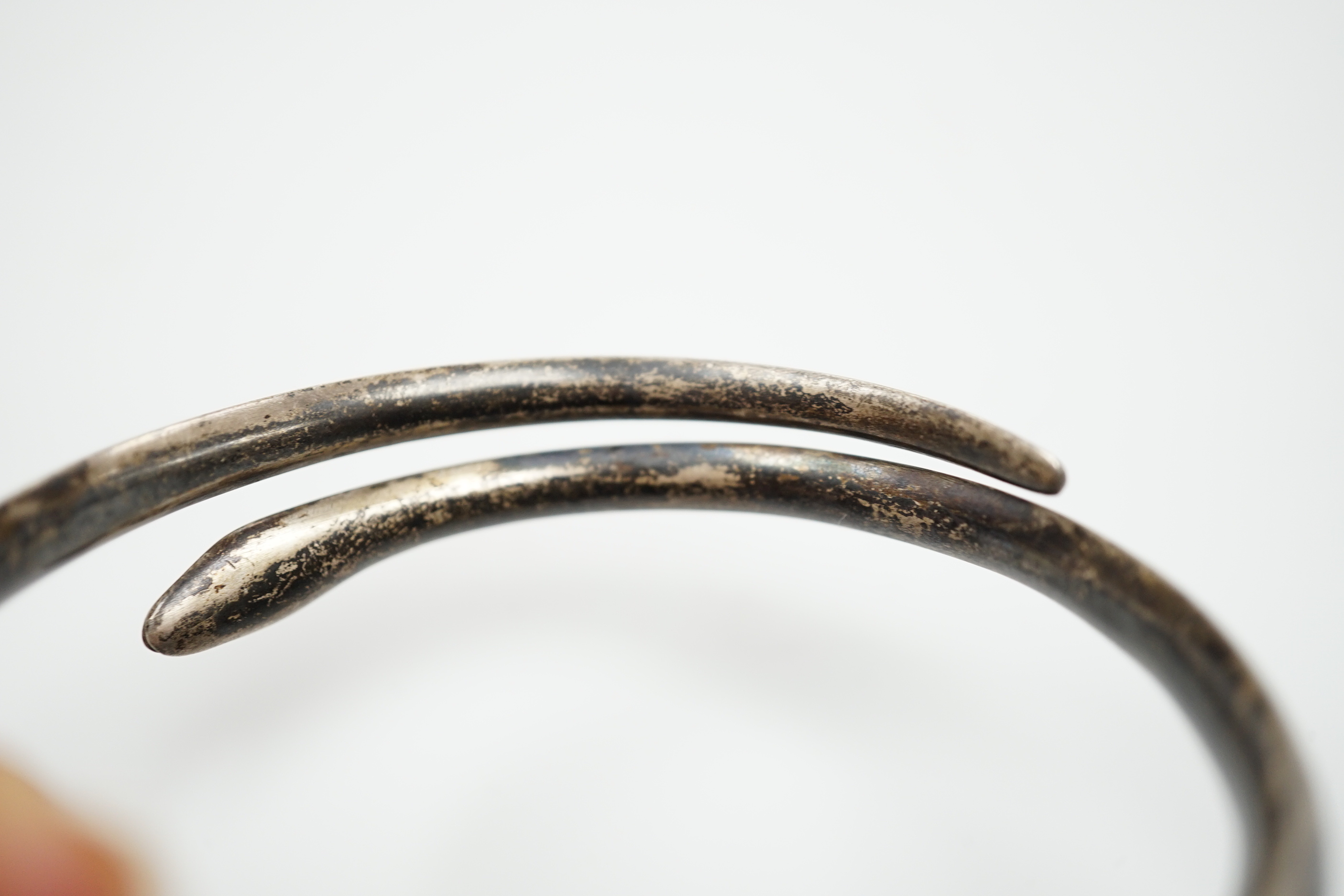 A white metal and niello serpent bangle, decorated with scene of a camel train.